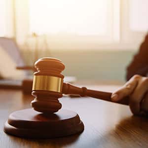 Gavel on wooden table with sunlight, suggesting a legal setting.