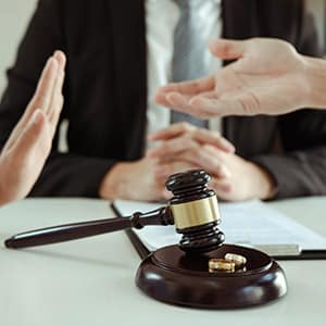 Gavel, rings on table; hands gesture, one stopping. Represents divorce proceedings.