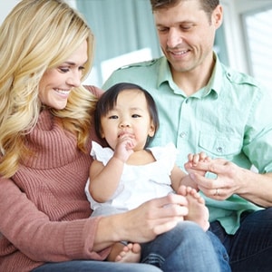 Happy parents playing with their baby, illustrating the basics of child support in Texas