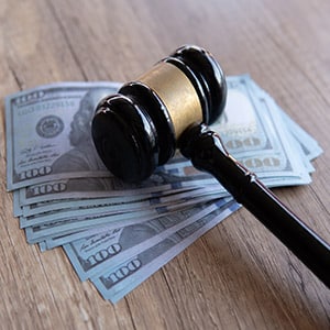 Gavel resting on US dollar bills, illustrating legal consequences for refusing to pay child support in Texas.