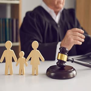 Judge’s gavel beside wooden family figures representing parents and child in a custody hearing